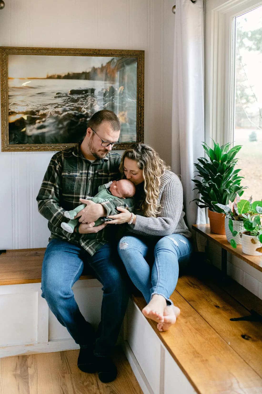 Jonge ouders op een vensterbank met hun slapende pasgeboren baby