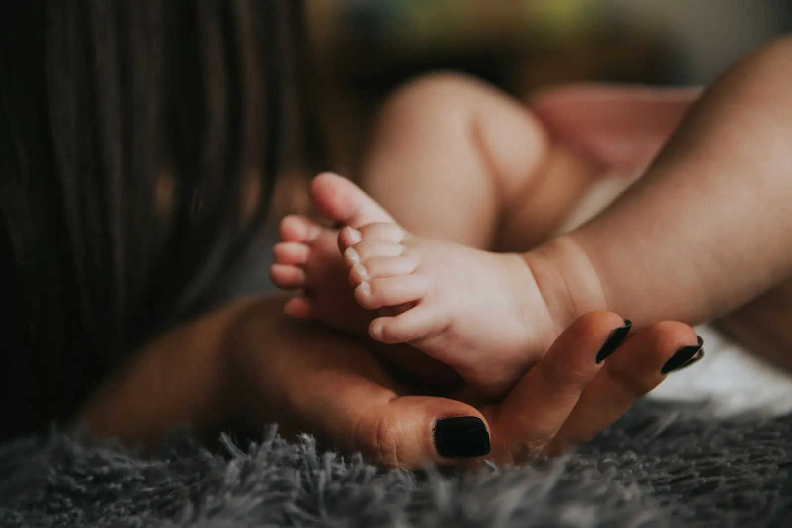 Een volwassen hand houdt de voetjes van een pasgeboren baby vast
