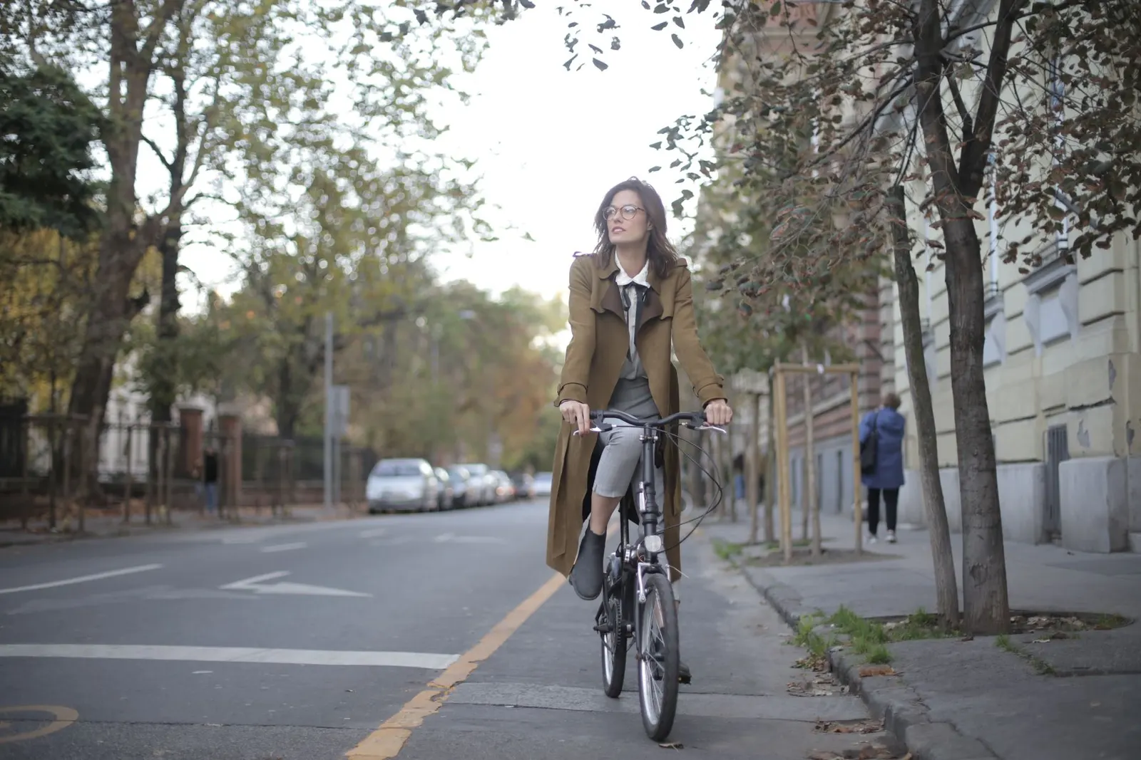 Een vrouw fietst door een woonstraat met bomen