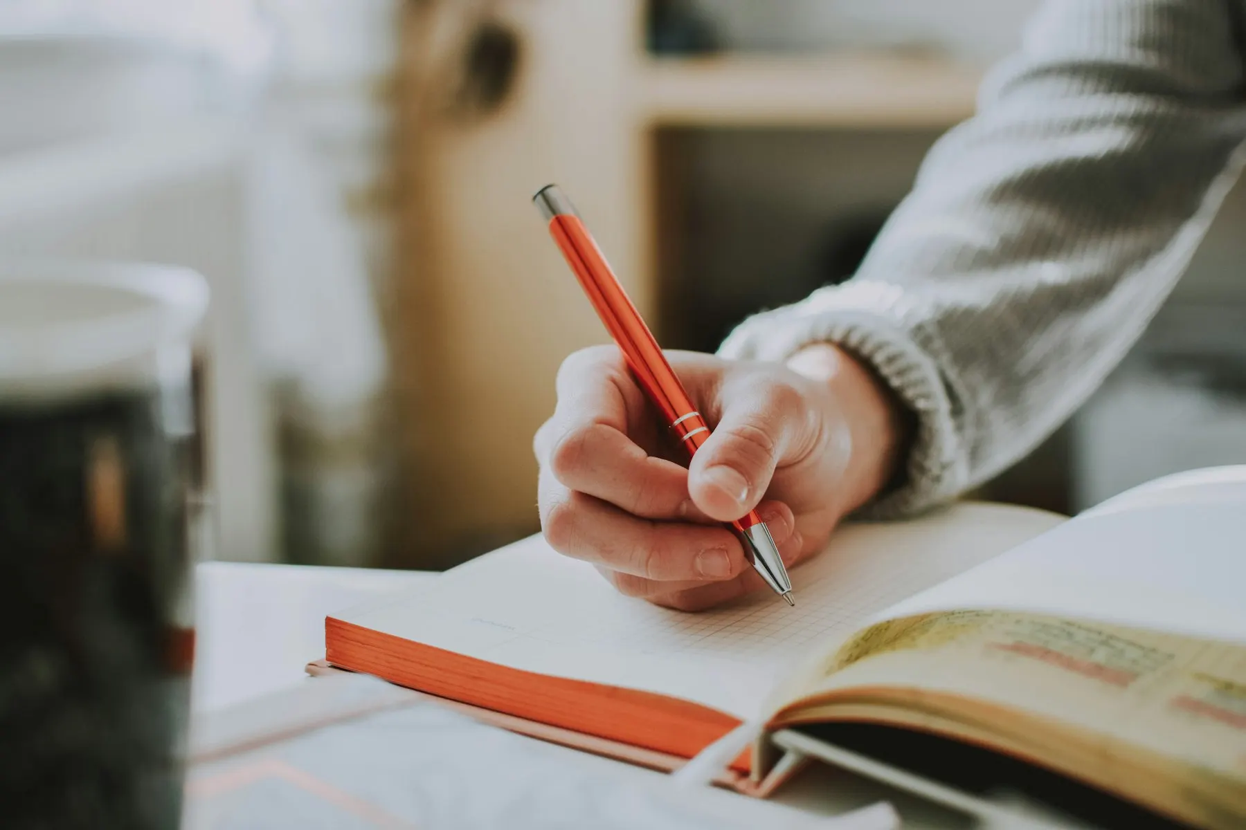 Een hand schrijft met een pen in een notitieboek
